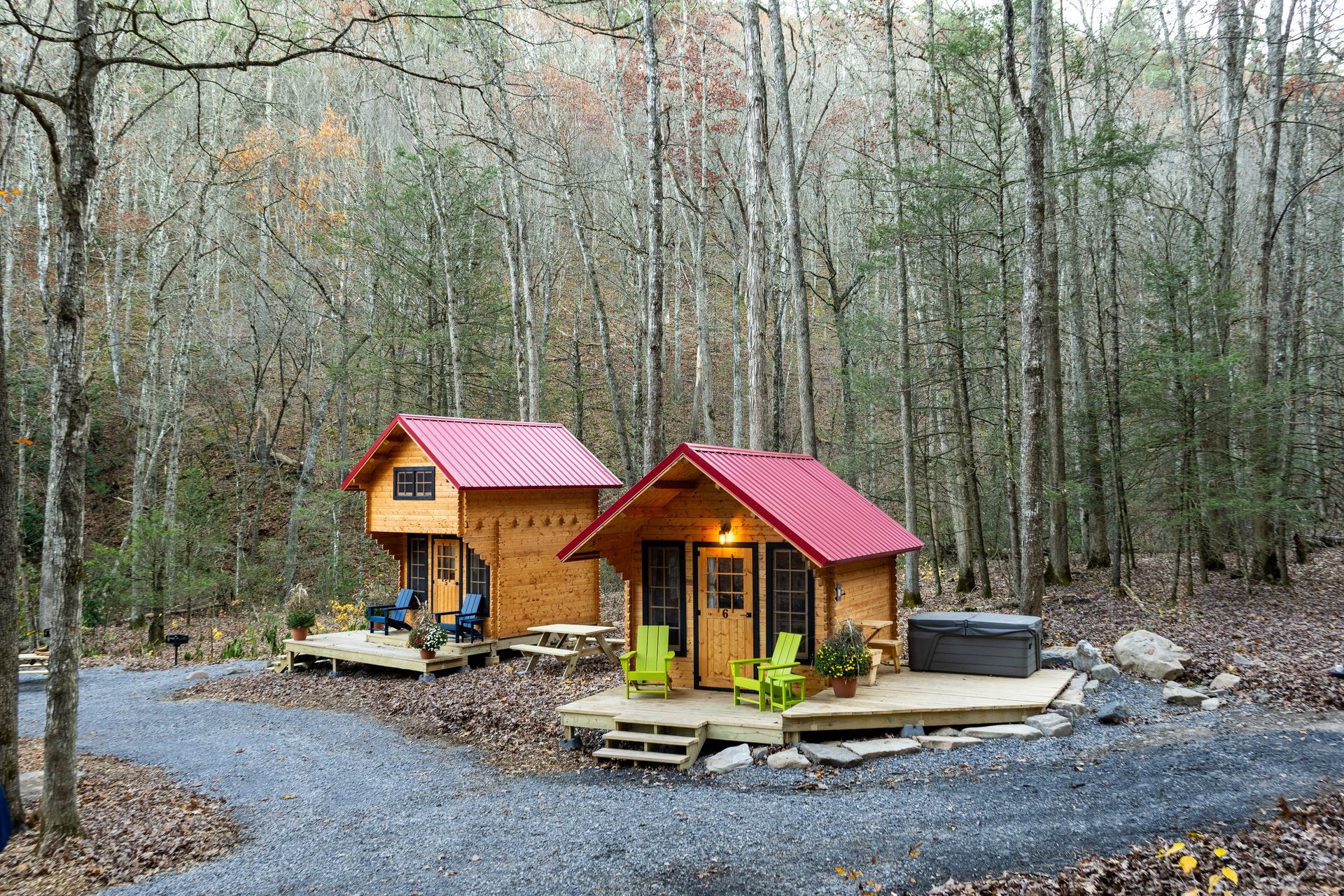 Two small wooden cabins with red roofs in a wooded forest clearing