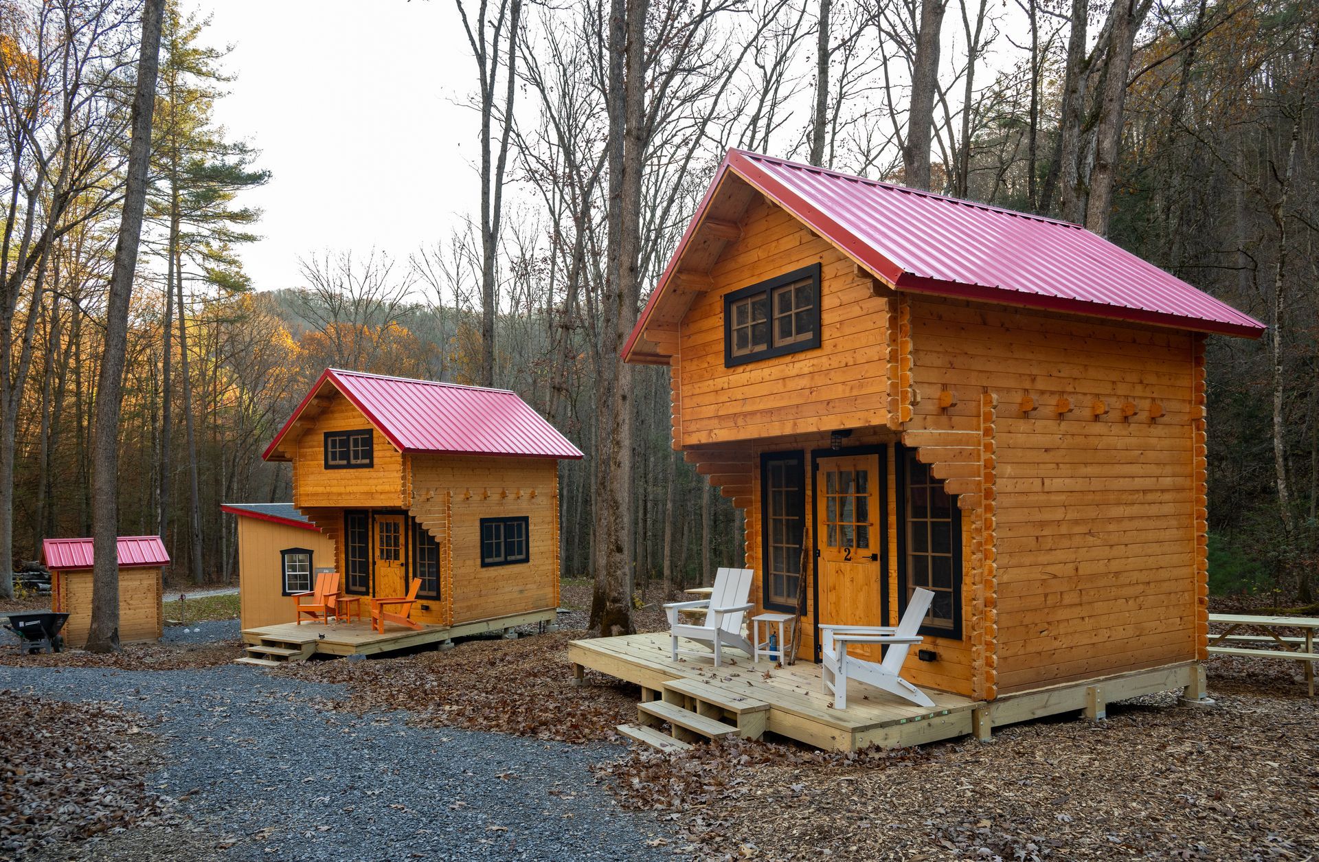 Two small wooden cabins with red roofs in a wooded forest clearing