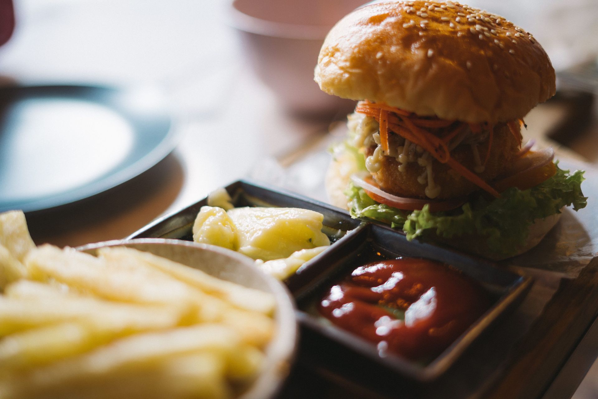 Burger with fries, lemon wedge, and ketchup on a wooden tray, close-up in a restaurant setting