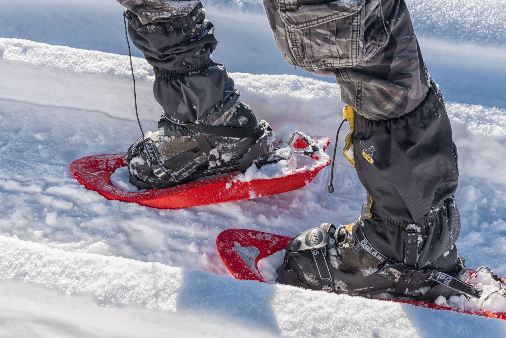 Person snowshoeing on red snowshoes through deep snow