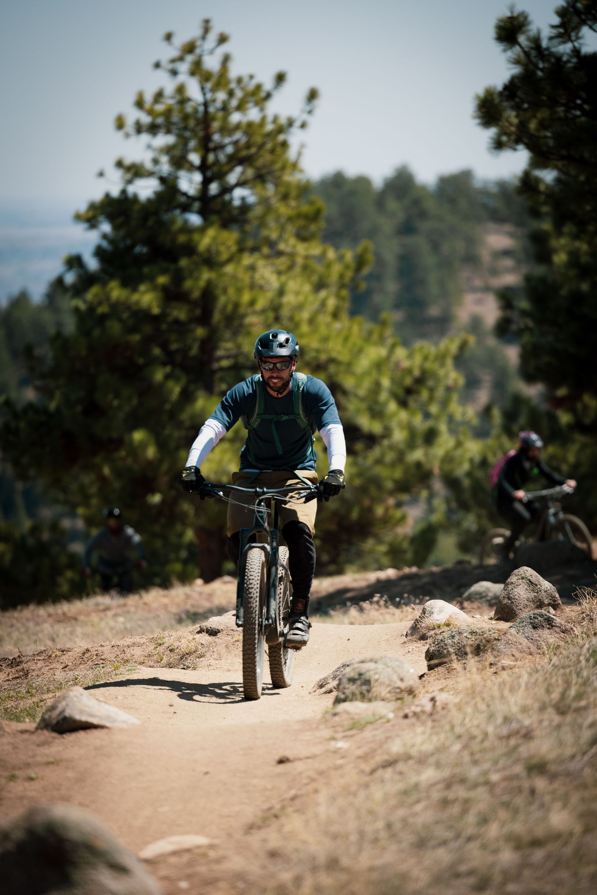 Mountain biker in a blue jersey riding on a dirt trail through a wooded area
