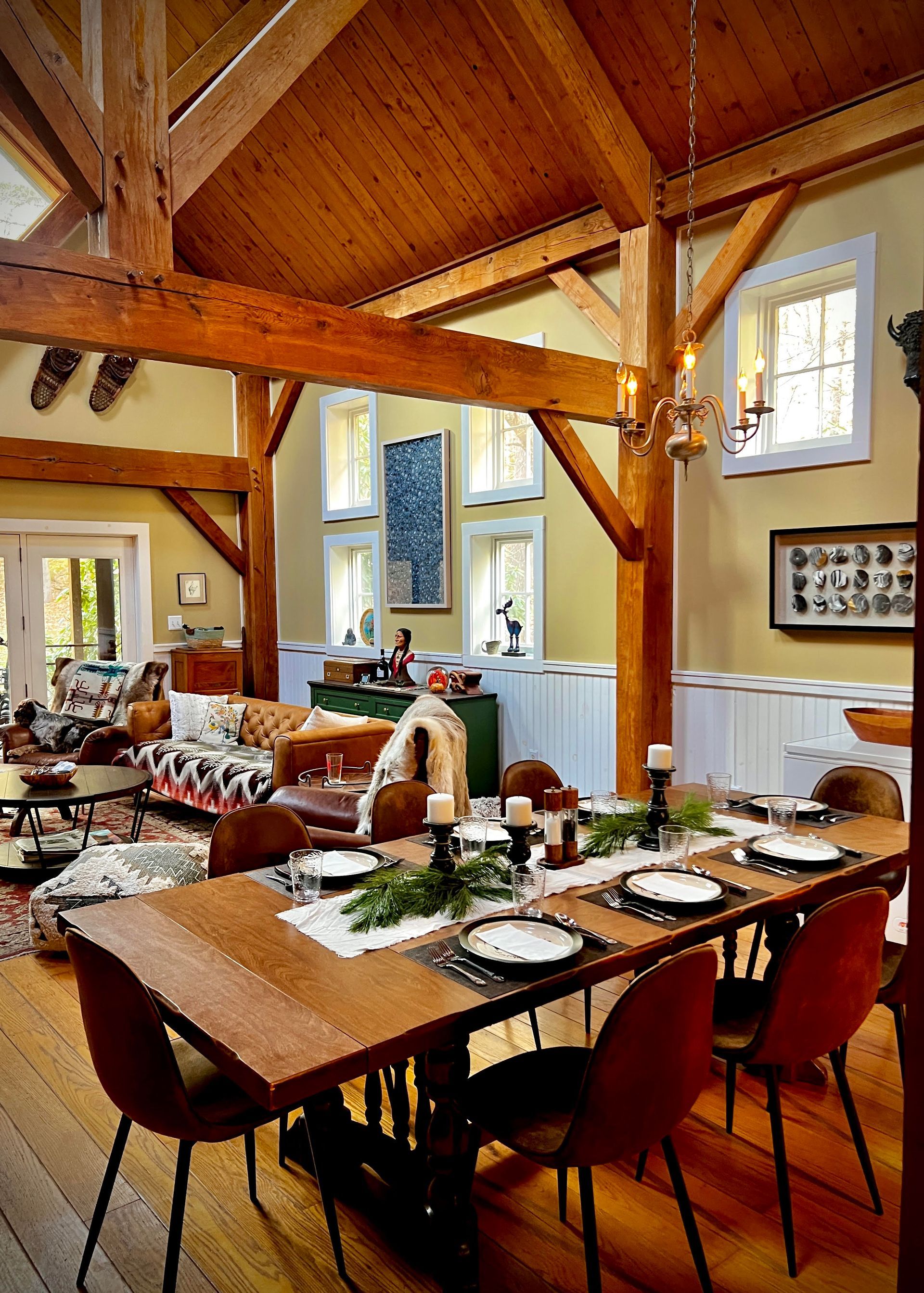 Rustic dining room with wooden beams, long tables set for a meal, and large windows