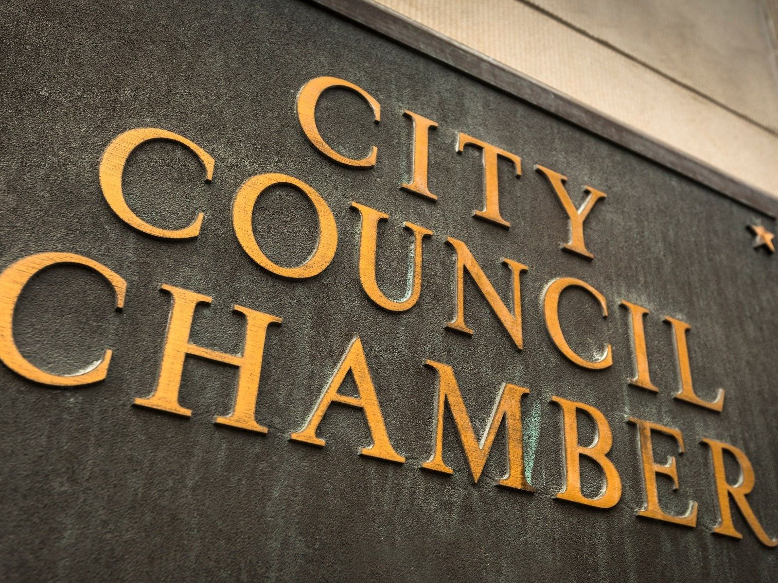 Gold letters reading “CITY COUNCIL CHAMBER” on a building wall