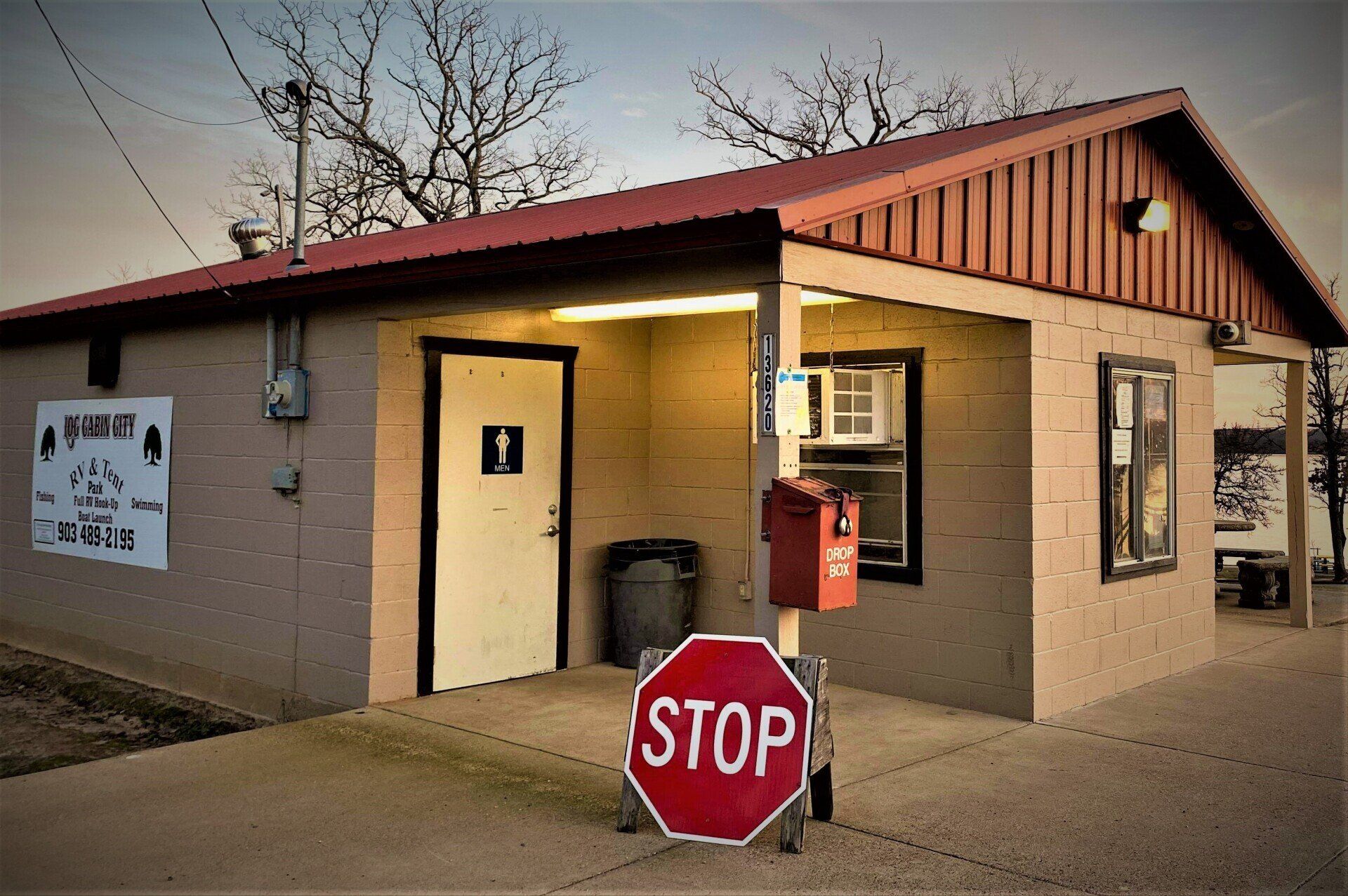 Small tan building with a red roof and a red STOP sign at the entrance.