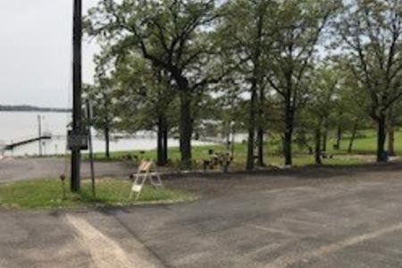 Rainy park with trees, benches, and a lake beside a wet paved path