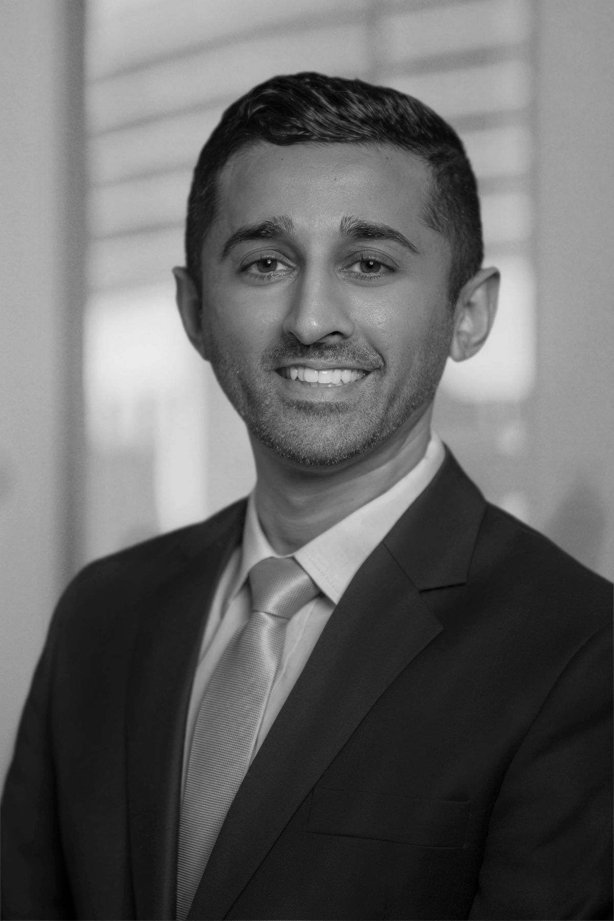Portrait of a smiling man in a suit and tie against a blurred office background