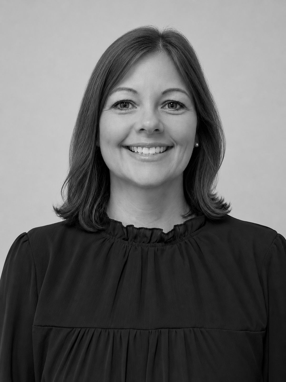 Smiling woman in a dark blouse against a light gray background