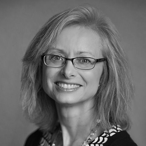 Portrait of a smiling woman wearing glasses in a black-and-white headshot