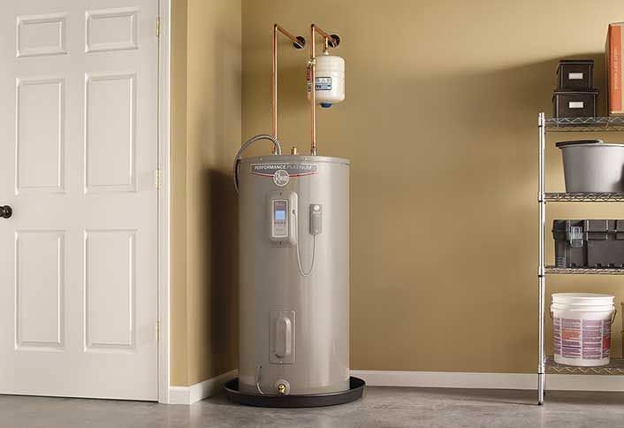 Water heater and expansion tank in a beige utility room beside a white door and shelving unit
