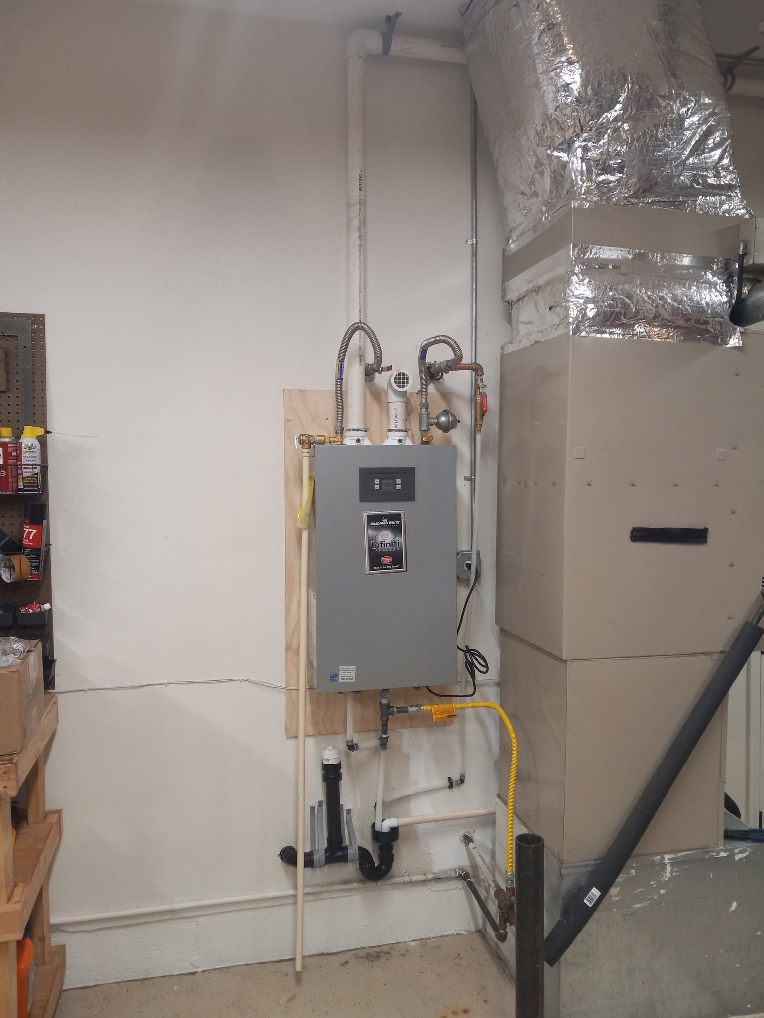 Wall-mounted electrical panel with exposed wiring beside large silver HVAC ductwork in a utility room