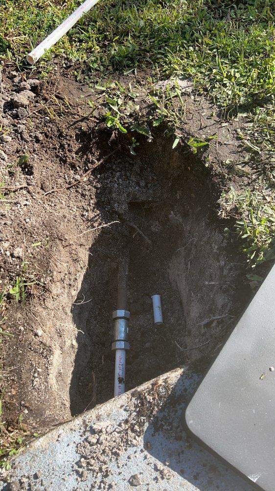 Open dirt trench beside a concrete slab, with grass around the edges.