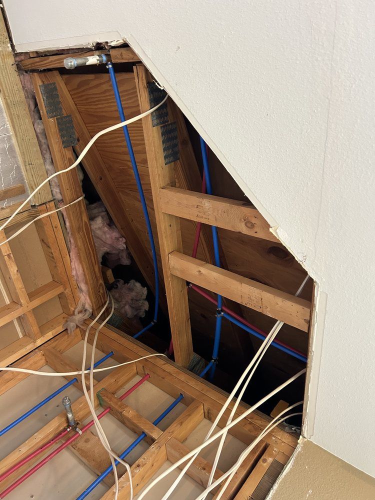 Exposed wall framing with blue and white electrical wires in an unfinished interior renovation area
