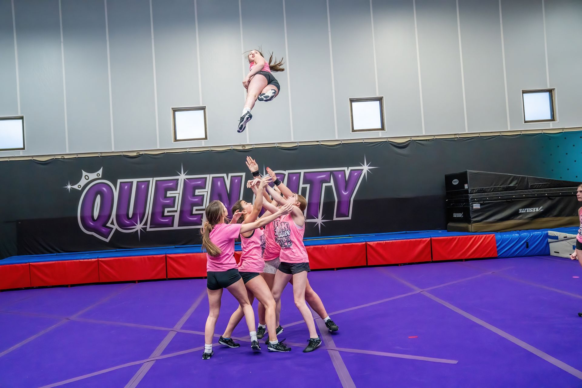 A group of cheerleaders are performing a trick on a trampoline.