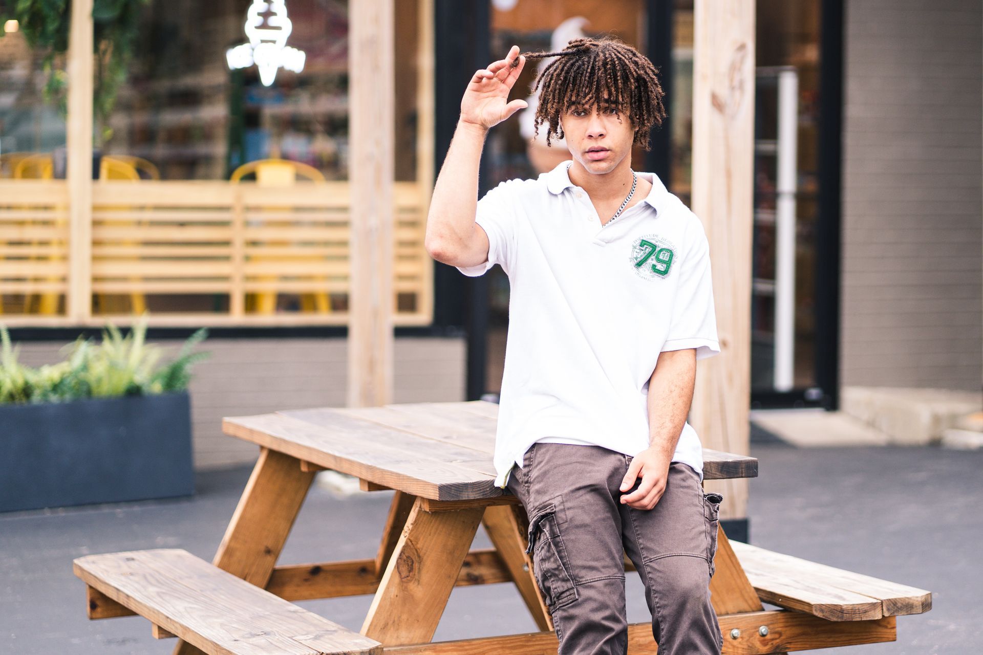 A young man is sitting on a wooden picnic table.