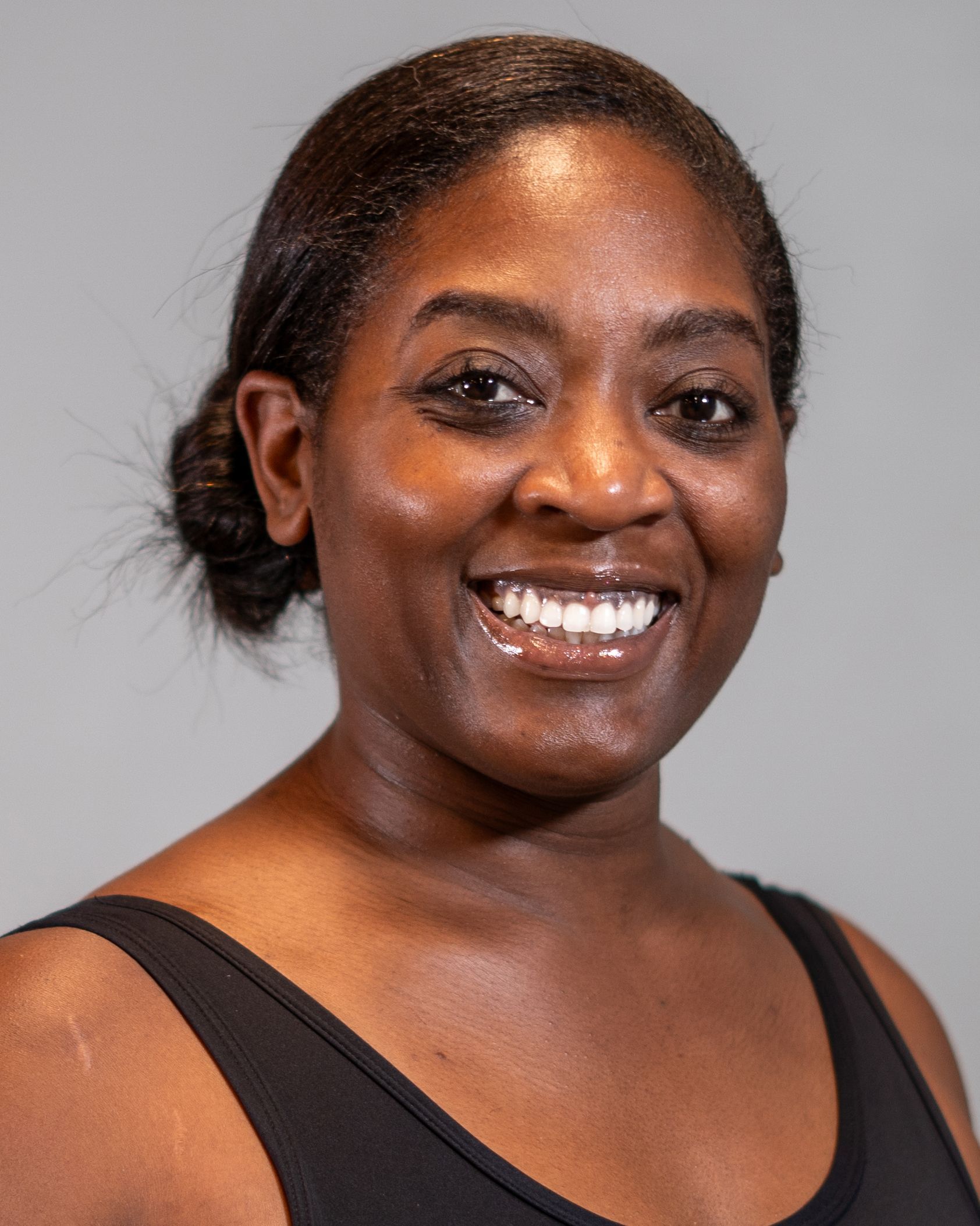 A woman in a black tank top is smiling for the camera.