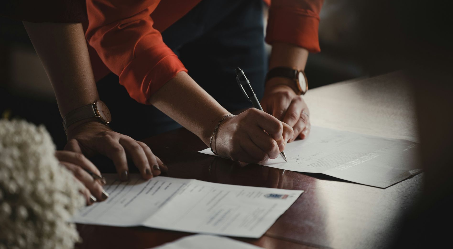 Photo of two people signing document, representing a relationship with a good property manager
