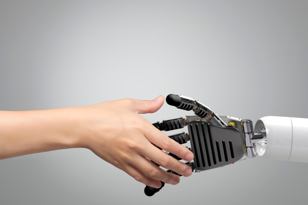 Human hand reaching to shake a robot hand on a grey background in reference to AI and ageism in legal recruitment