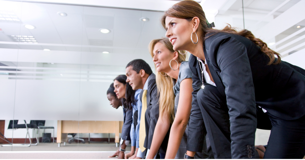 Four office workers lean forward in a modern conference room, focused on something ahead.