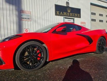 Bright red Corvette with black rims parked outside 