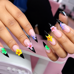 Hands with long purple and black stiletto nails, decorated with colorful flower nail art.