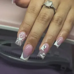 Hand with pink-and-white nail art, including geometric webs, hearts, and ghost designs.