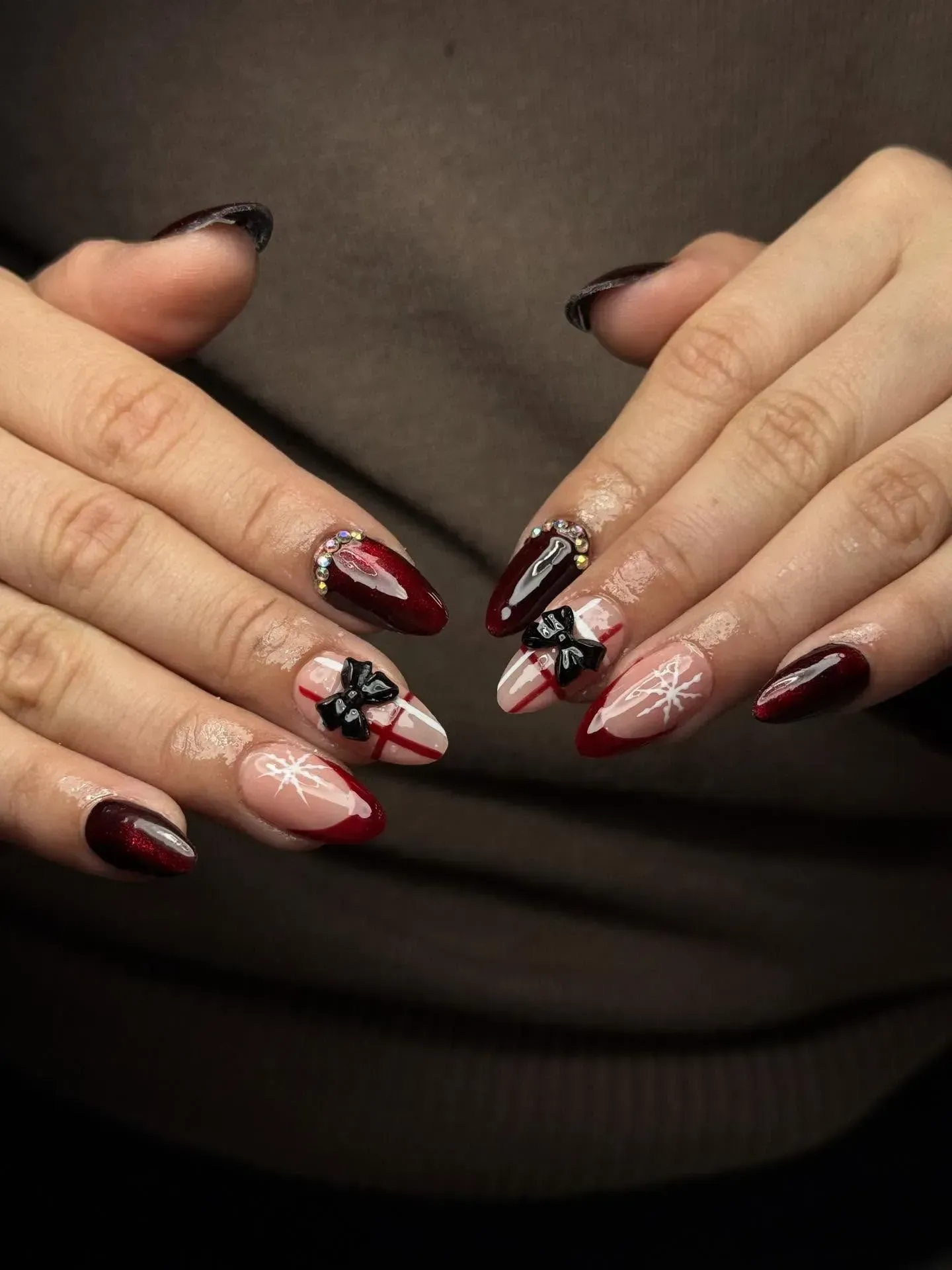 Hands with burgundy and pink manicured nails featuring black-and-white floral nail art.