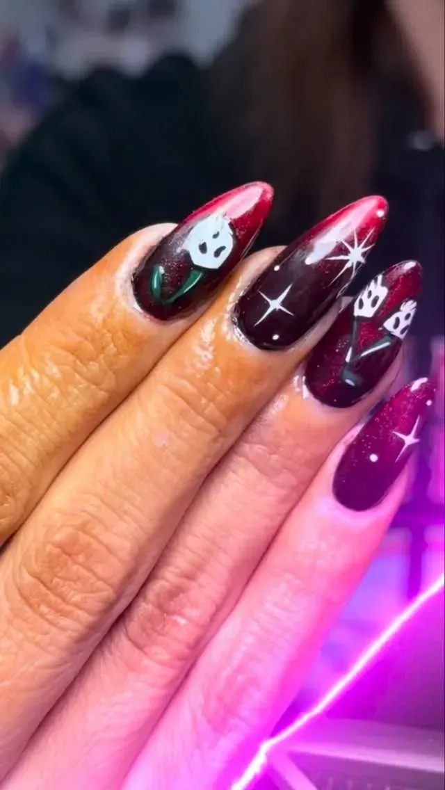 Close-up of long black and pink glitter nails with white star and skull nail art