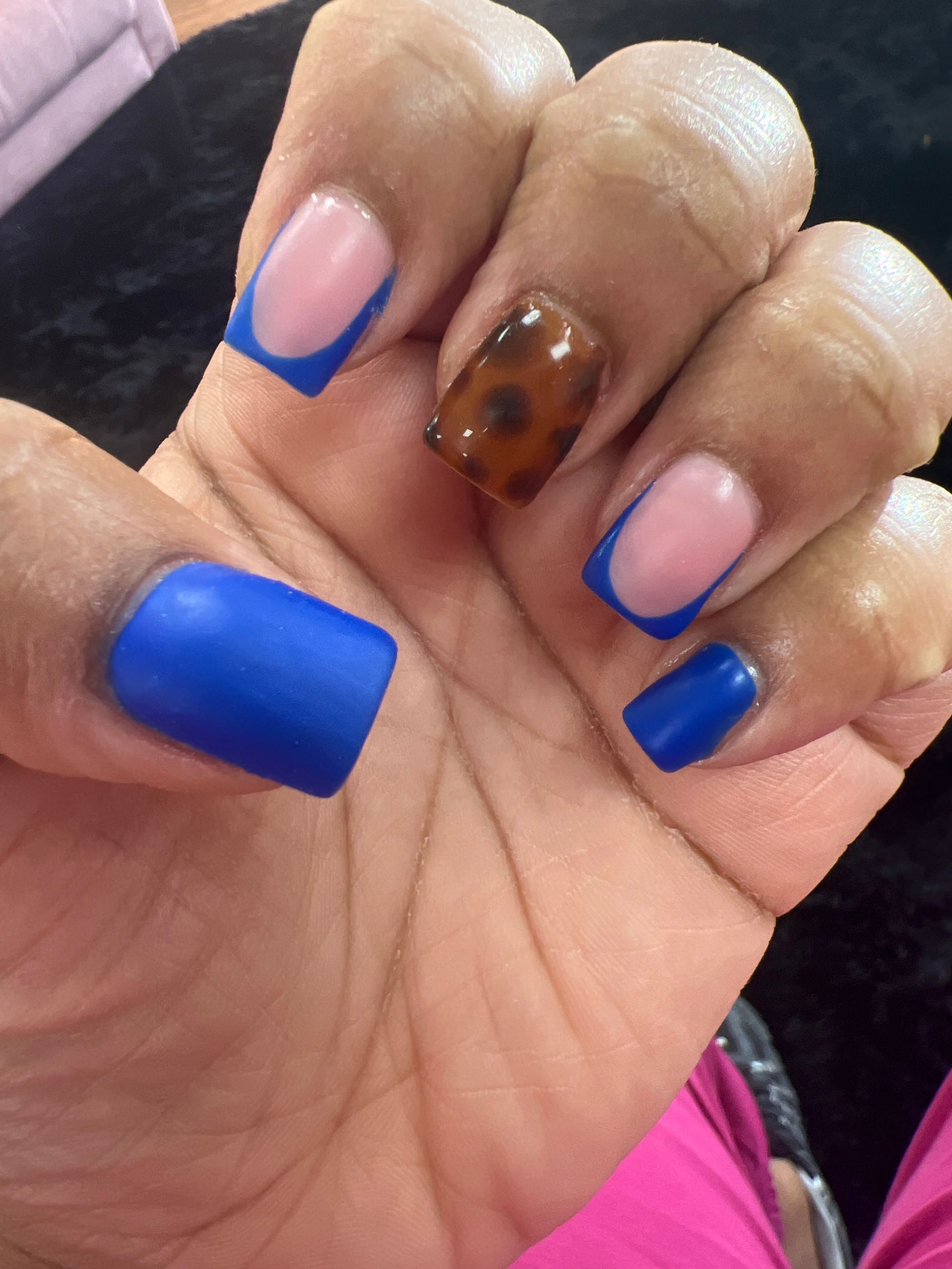 Hand with long blue and pink nails and one brown marbled accent nail