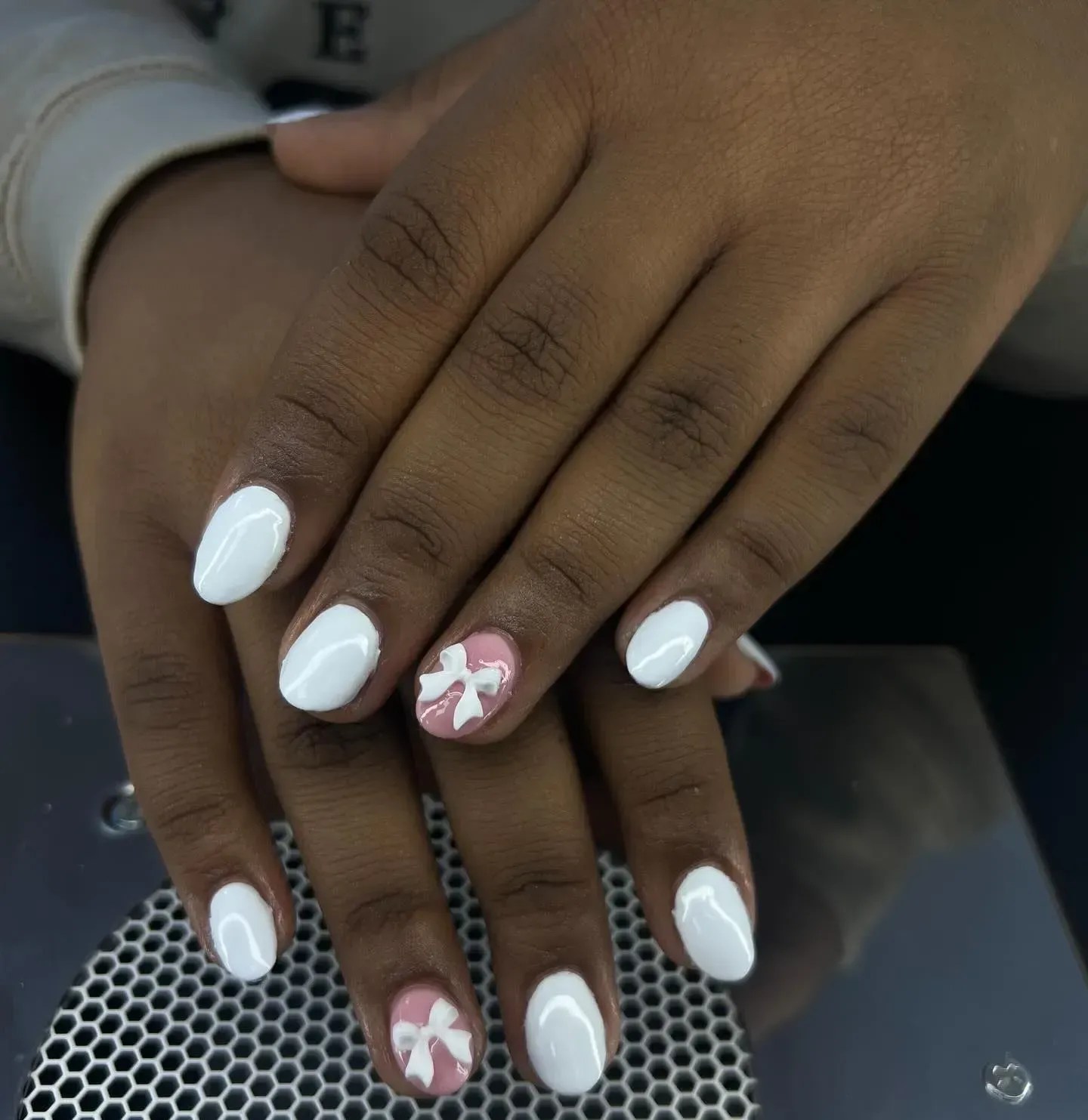 Hands with white and pink floral manicured nails resting on a patterned surface