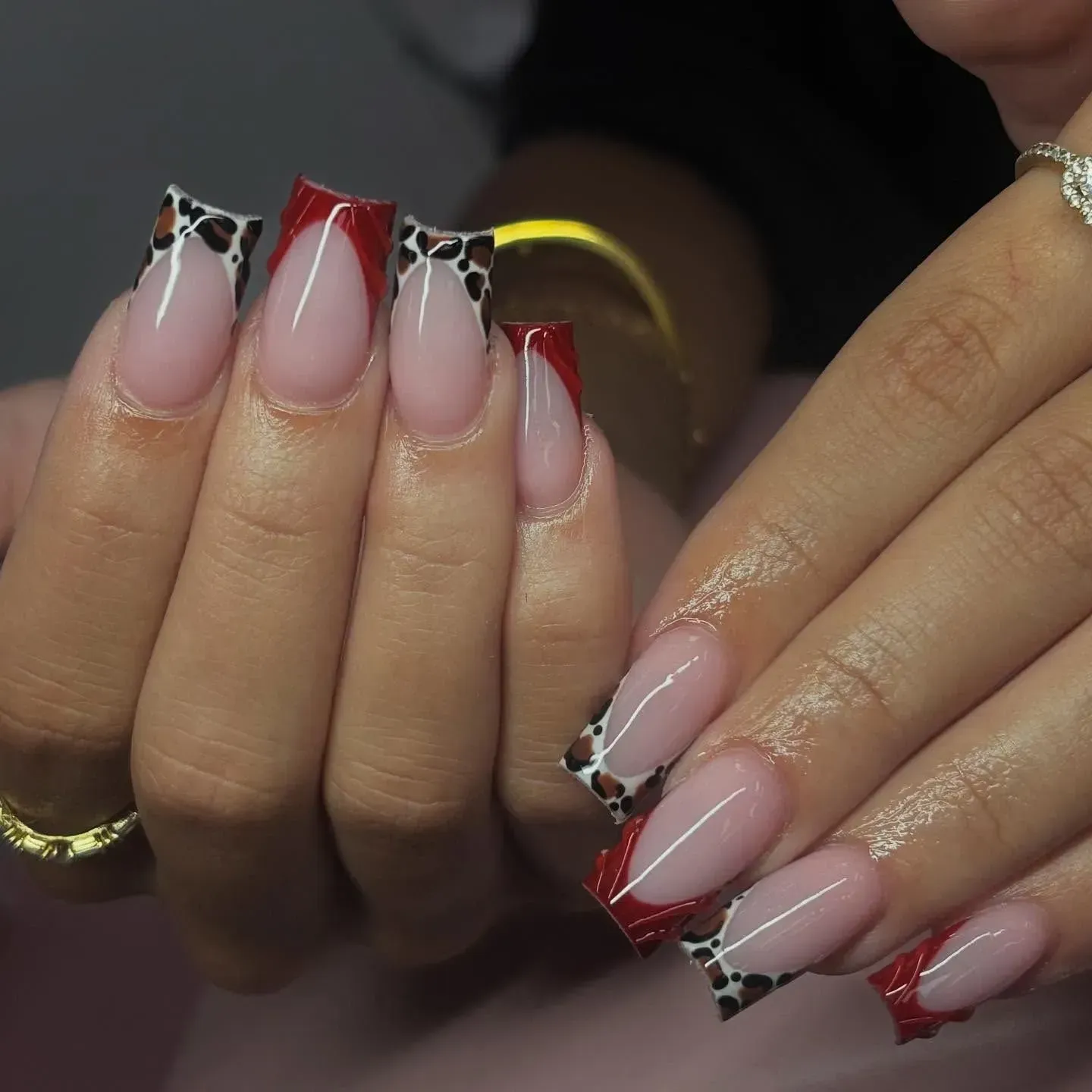 Close-up of hands with red and nude French manicure and black spotted nail tips