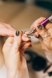Hands filing a fingernail with a purple manicure tool