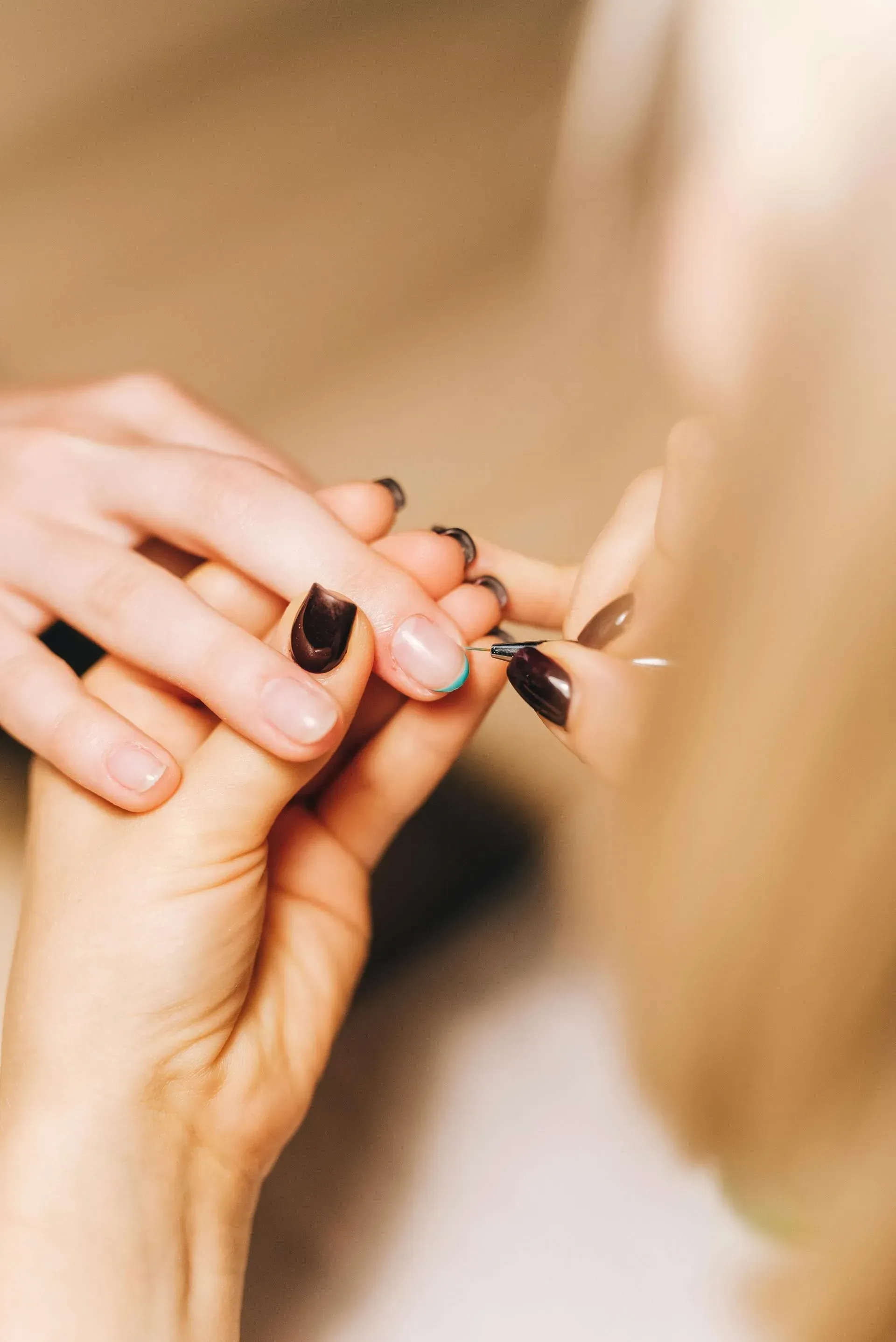 Hands painting nails black in a close-up beauty salon scene