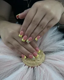 Hands with pink and yellow nails resting on a fluffy white surface and woven accent.