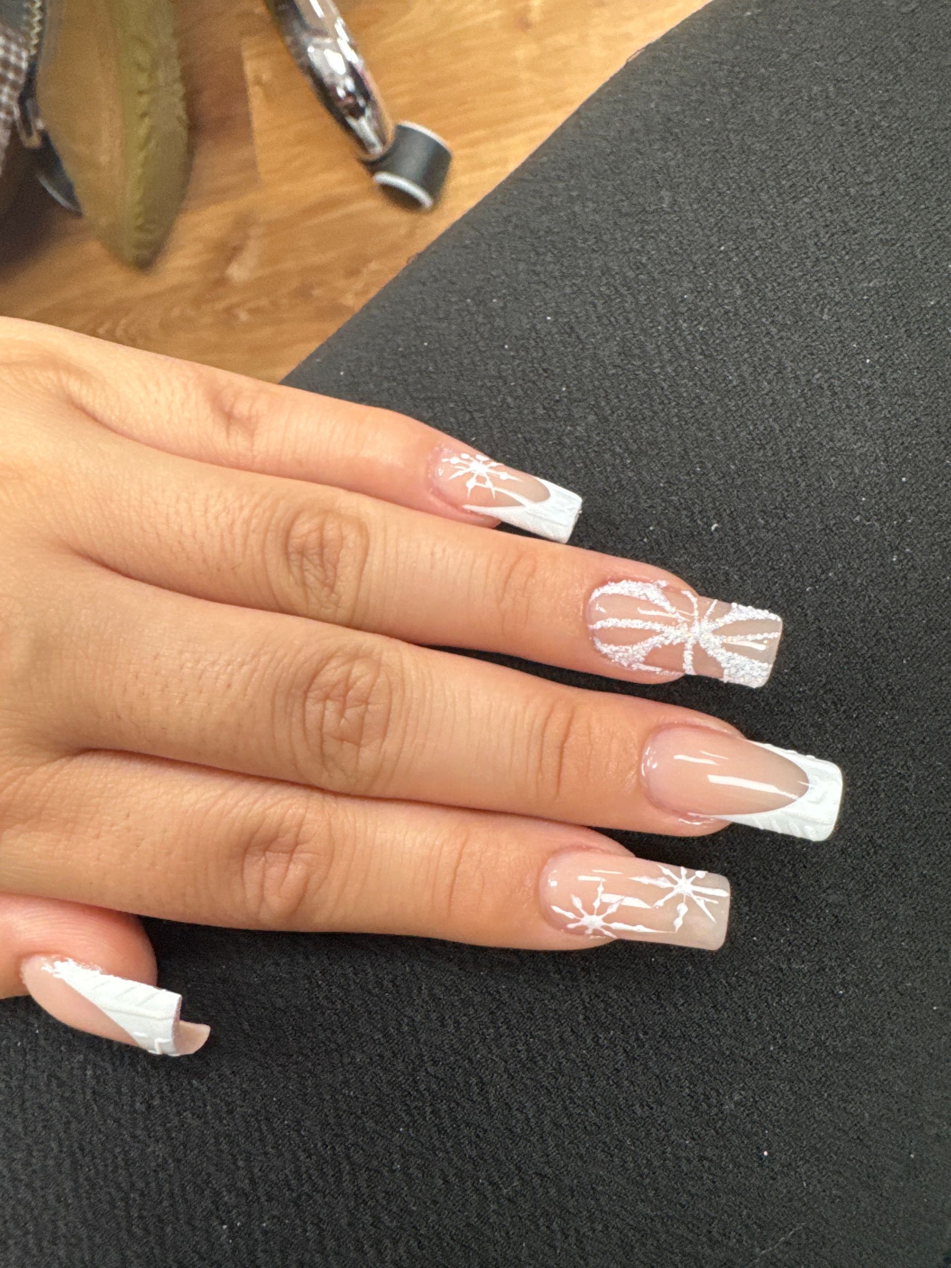 Hand with long nude and white French-tip nails resting on a black surface