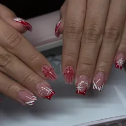 Hands with red and white glittery star nail art resting on a table