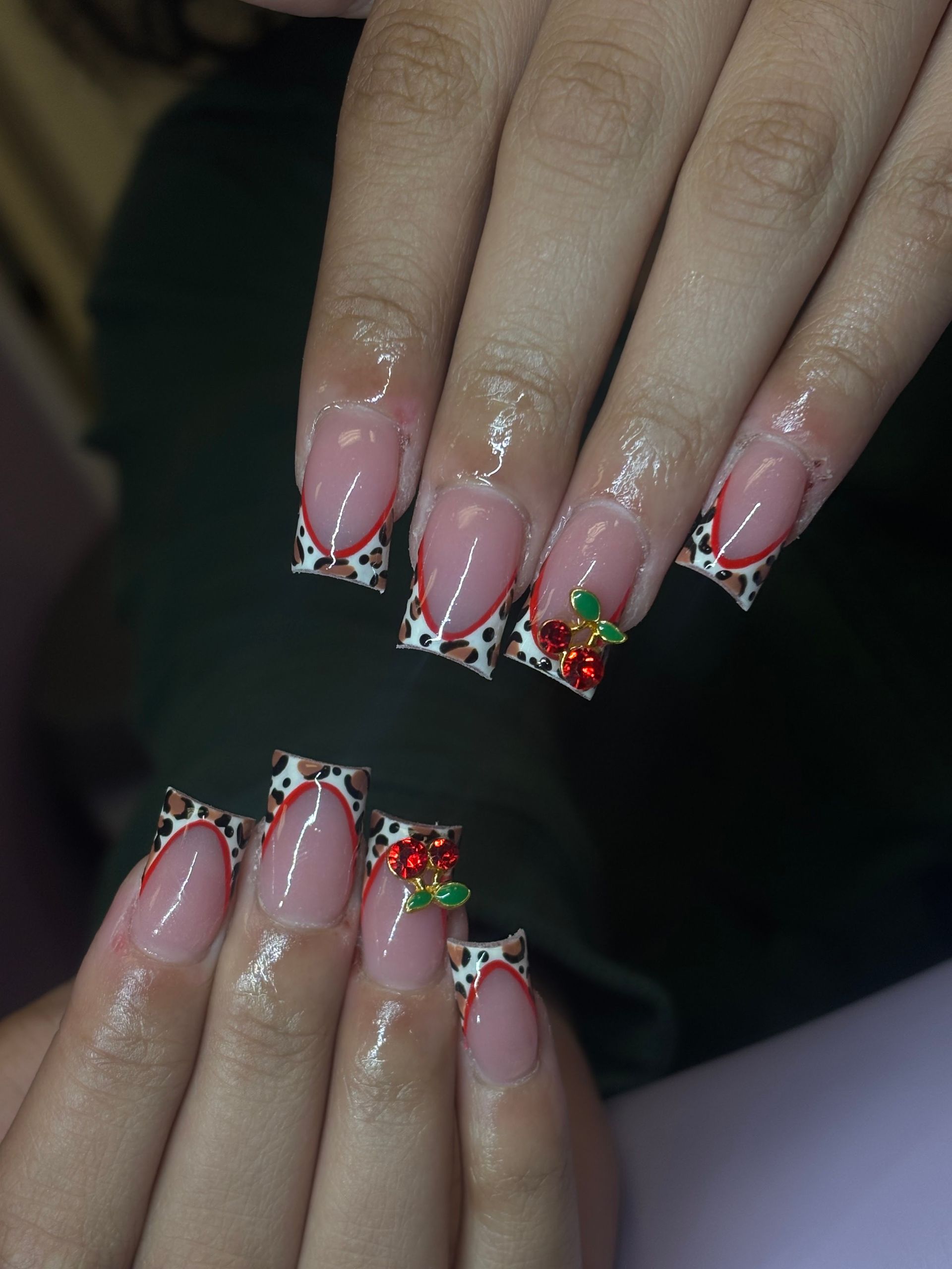 Two hands with pink glitter nails and red-green holiday nail art on dark background