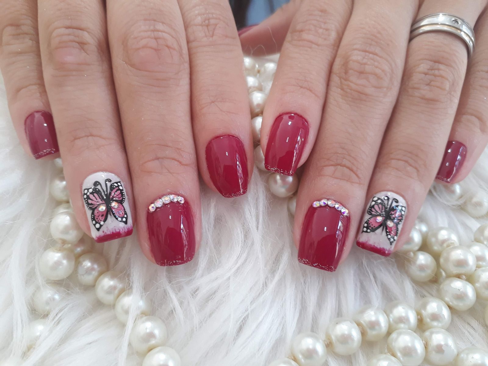 Hands with long white nails resting on a pink manicure hand rest.