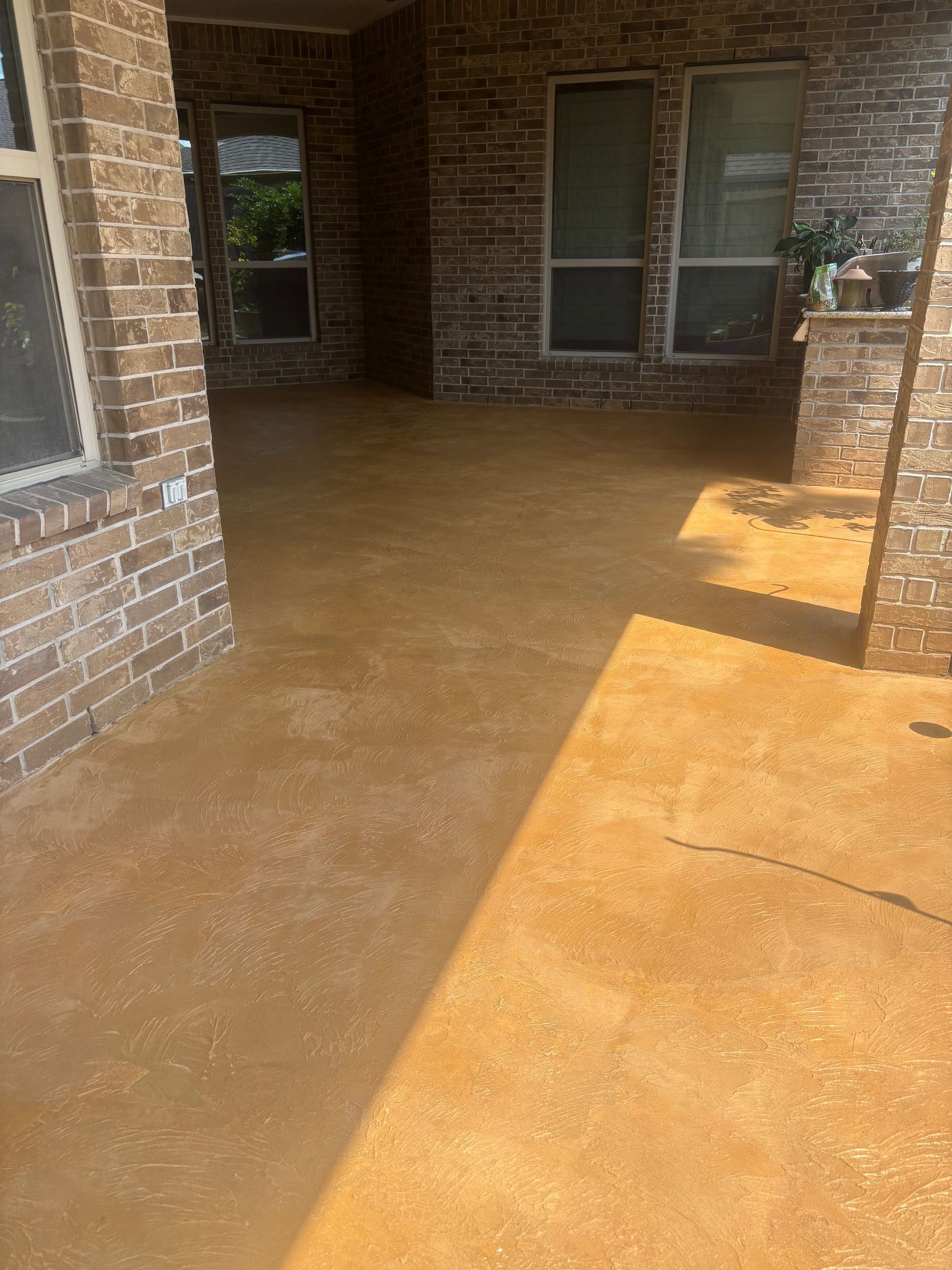 Brick-covered front porch with wet concrete floor and sunlight near the entry door