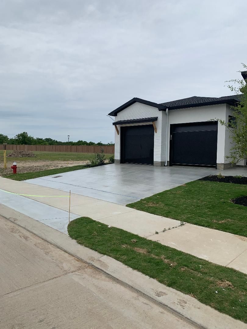 Suburban house with two black garage doors, wet driveway, and a cloudy sky