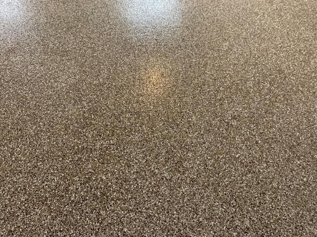 Close-up of a speckled brown and beige textured surface with a faint light reflection near the center