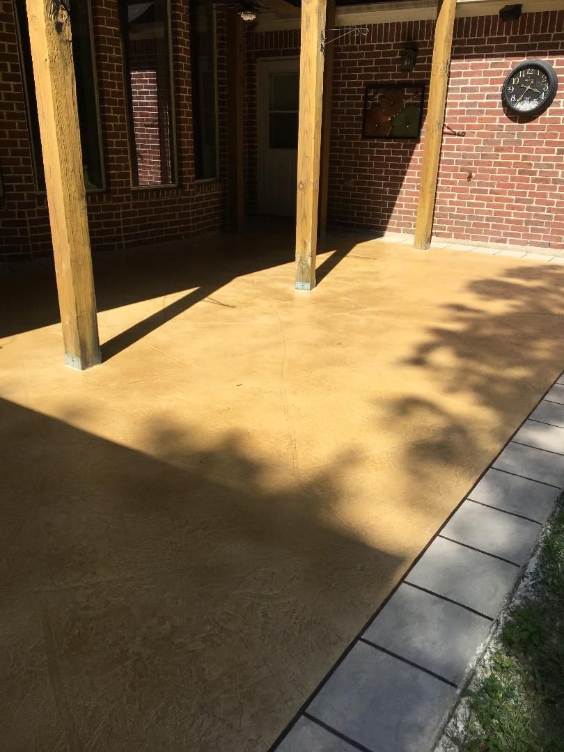 Shaded brick patio with wooden posts and sunlit concrete floor beside a tiled walkway