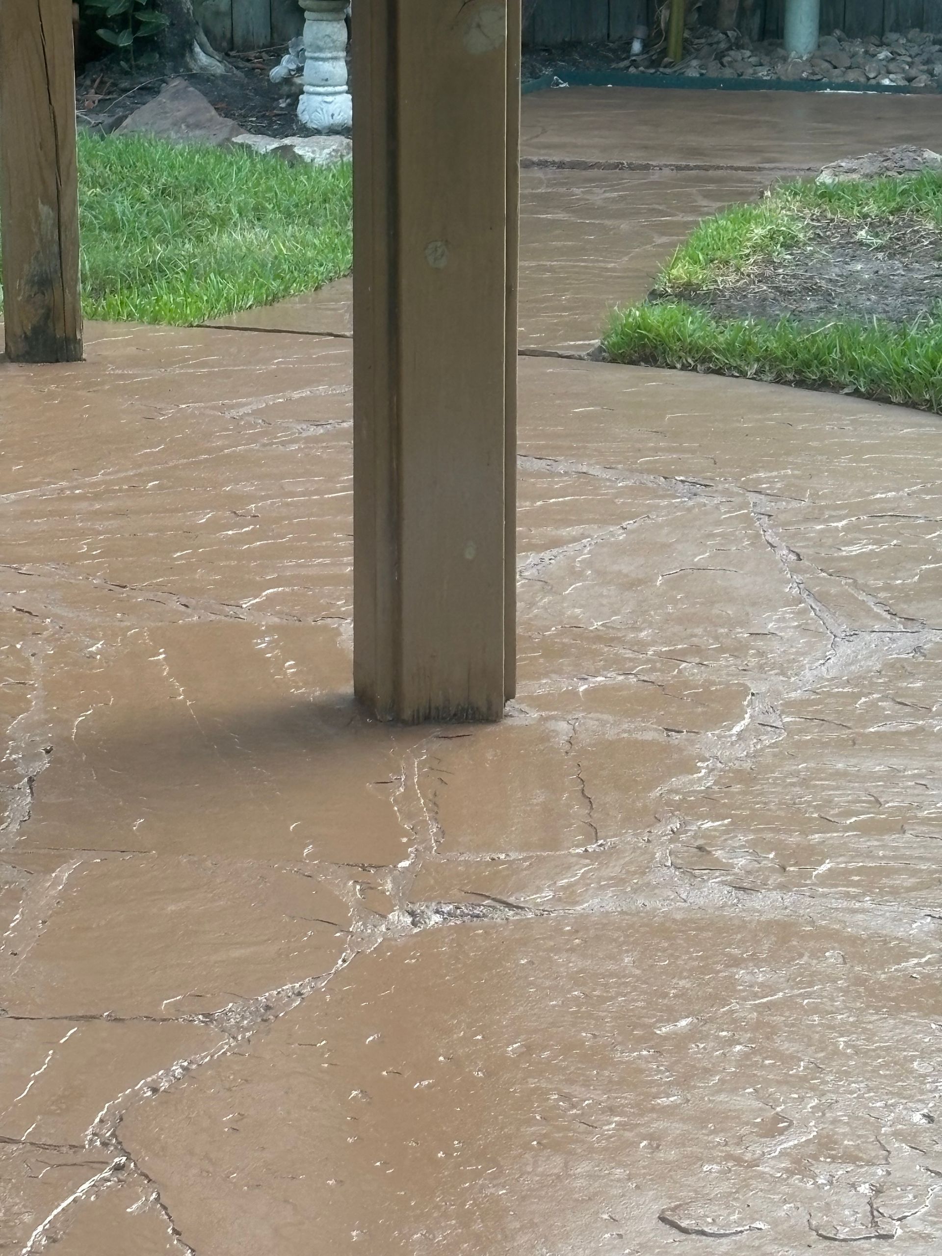 Muddy floodwater pooling around a wooden post on a covered porch during heavy rain