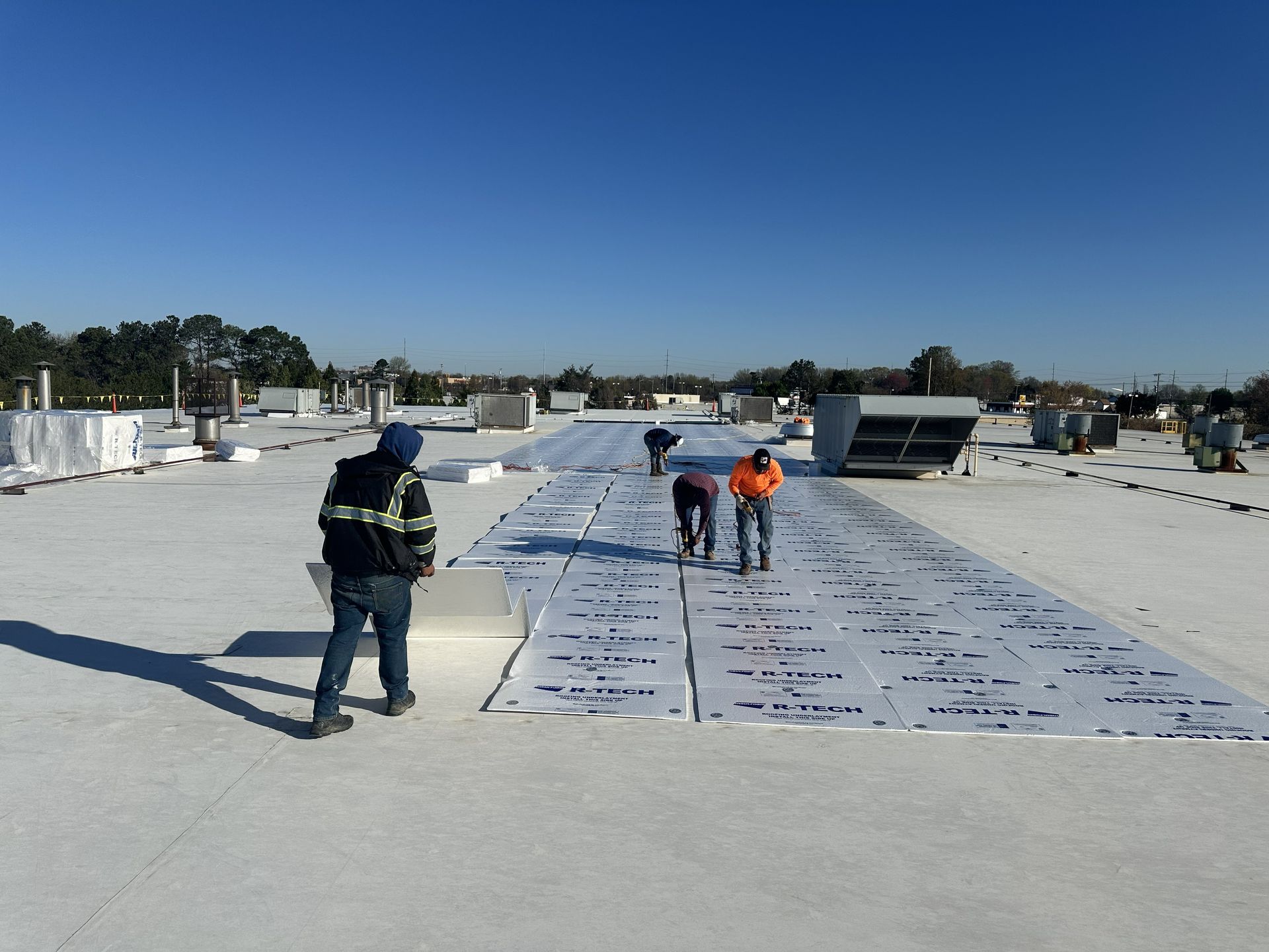 B&D Roofing Solutions crew installing roof insulation boards during Phase I of the commercial TPO roof recover at IMMI SafeGuard Seating in High Point, NC.