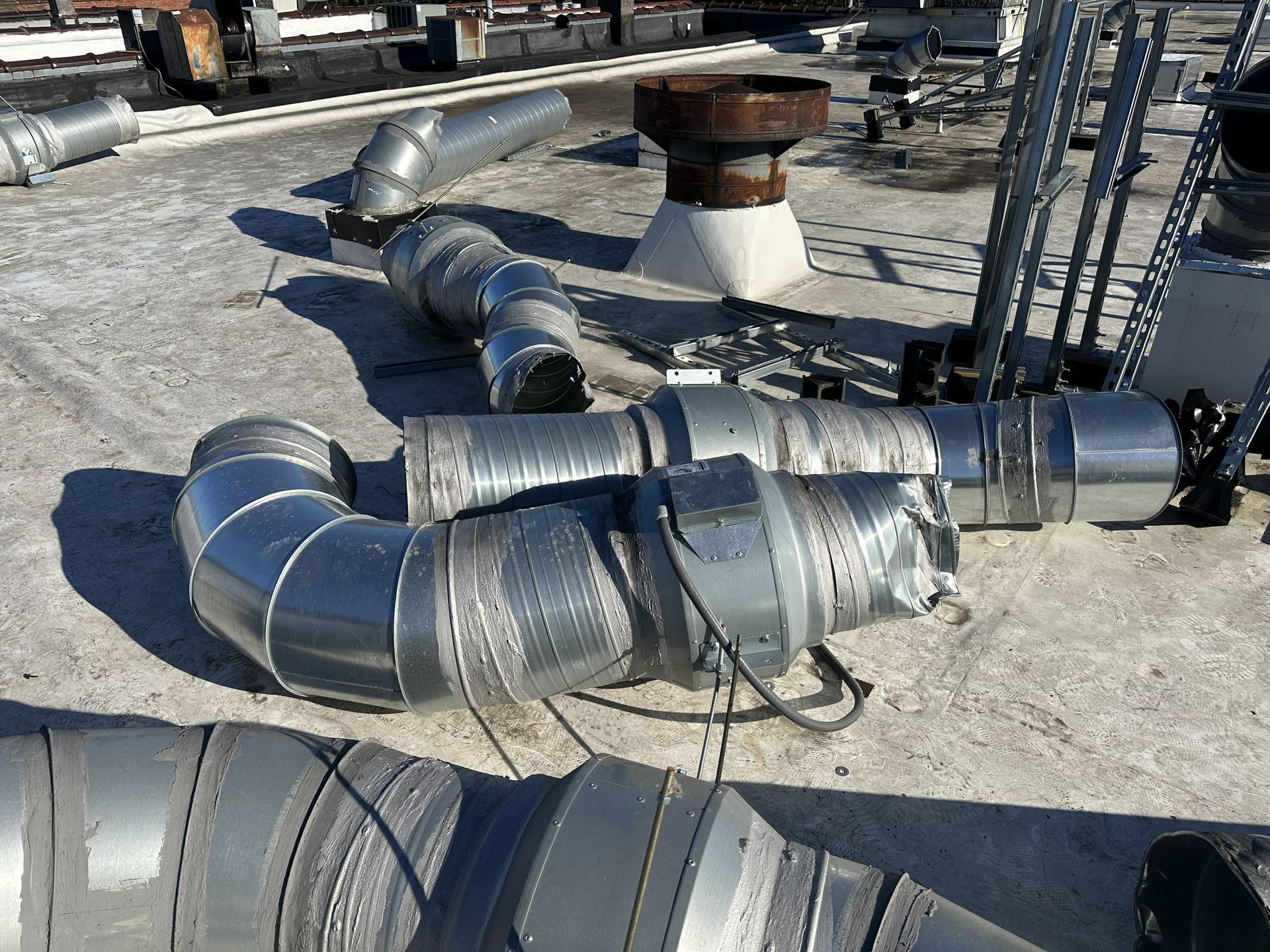 Abandoned rooftop mechanical equipment and ductwork before partial tear-off and Carlisle TPO roof recover by B&D Roofing Solutions at Franklin Properties on Lawndale Drive in Greensboro, NC.