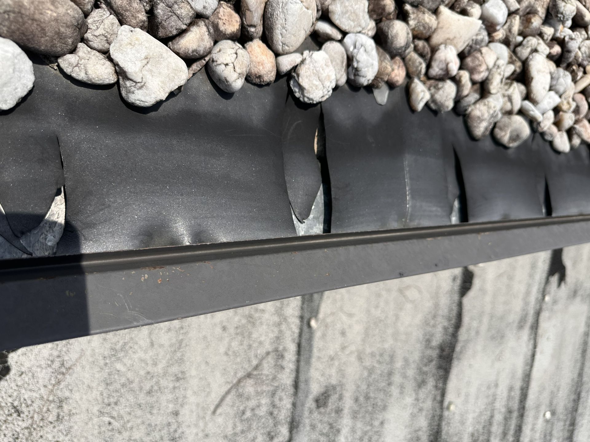 EPDM roofing membrane pulling away at the perimeter of a ballasted commercial roof.