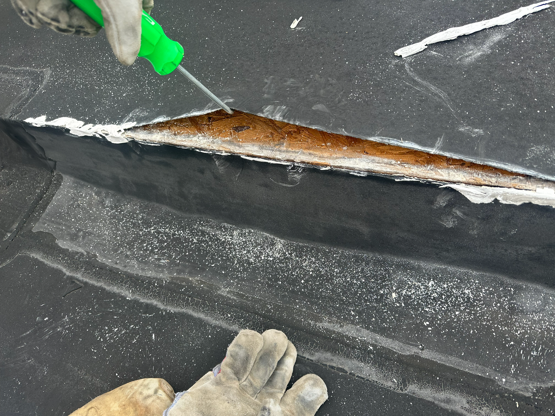 Bill Frey inspecting a commercial roof seam during a restoration evaluation to assess the condition of the roofing system.