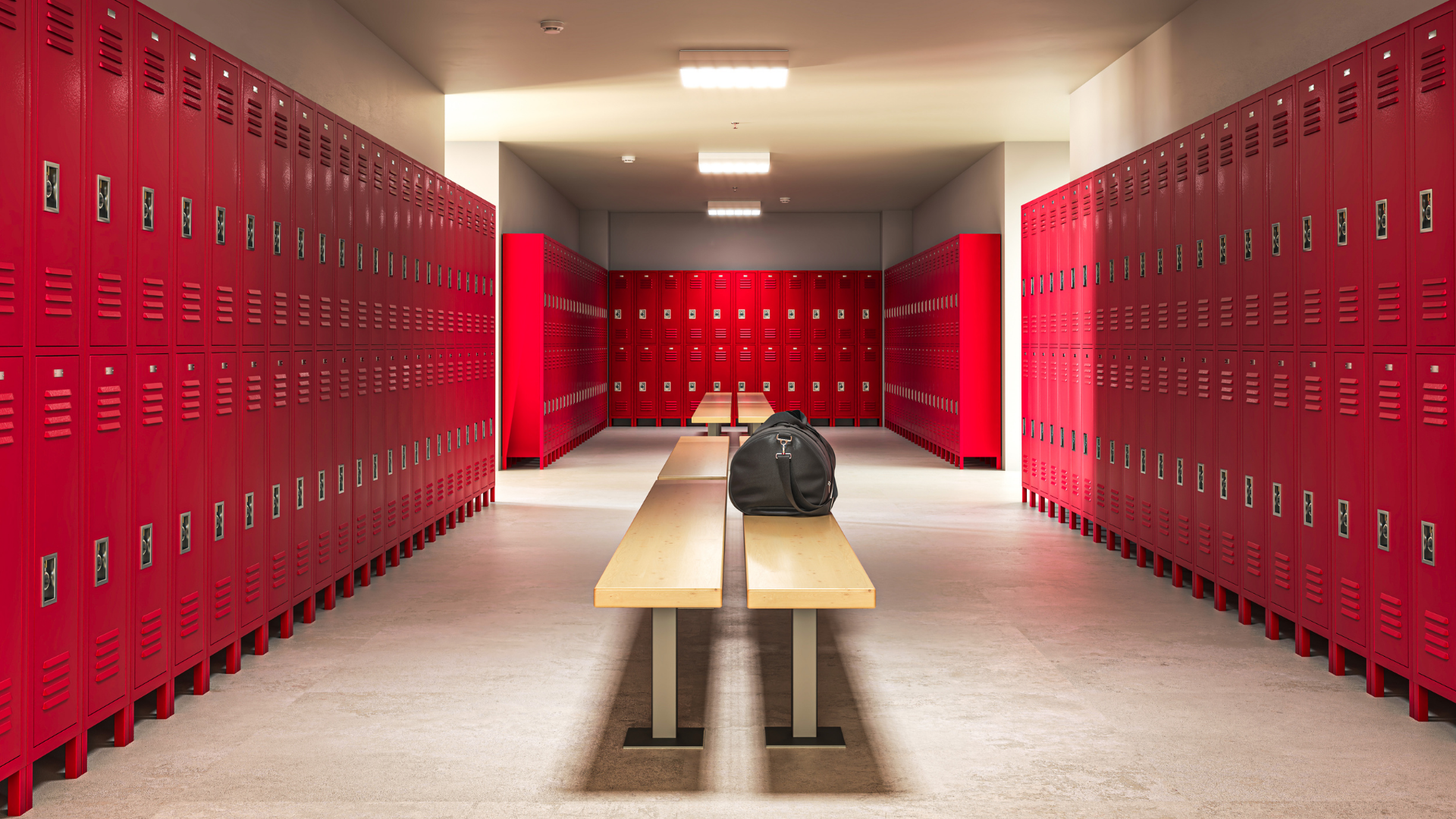 Red school lockers line a hallway, bench and backpack in the middle.