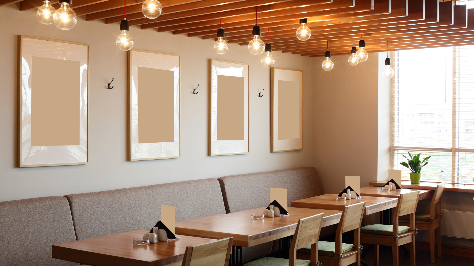 Restaurant interior with wooden tables, booth seating, framed art, and hanging lights.
