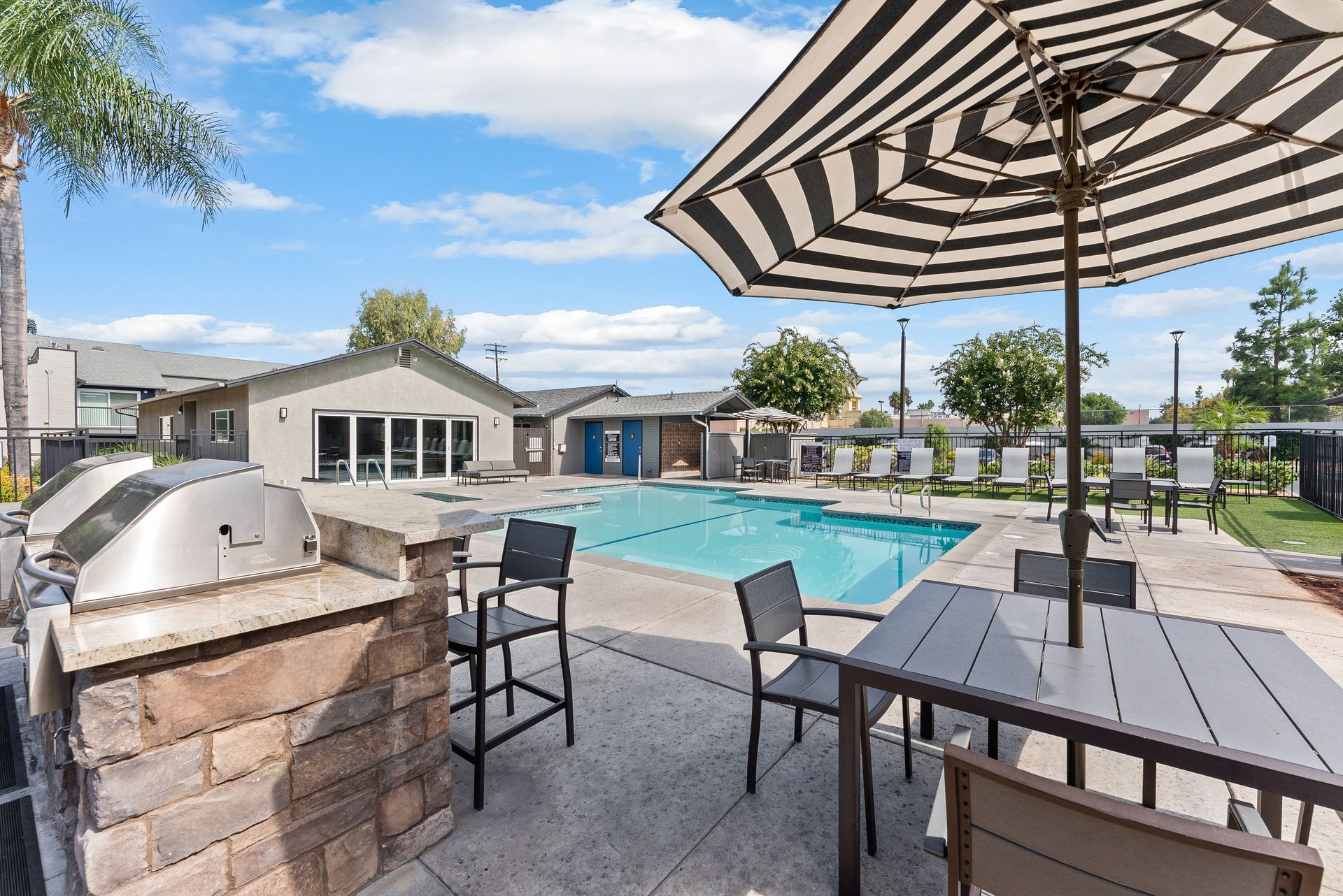 A black and white striped umbrella is sitting next to a swimming pool.