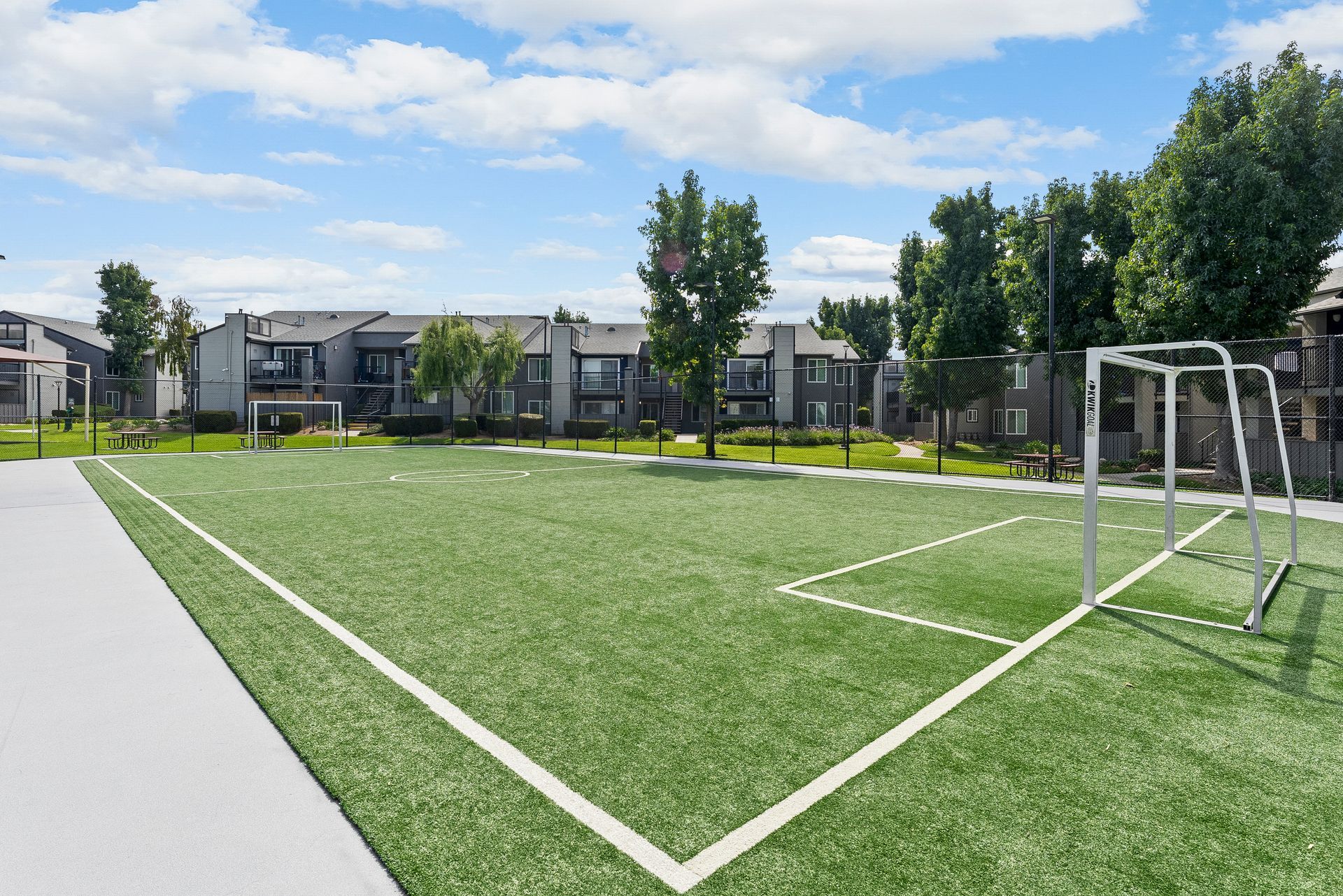 A soccer field with a goal in the middle of it in front of a building.